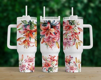 May include: Three white stainless steel tumblers with a floral design featuring pink lilies. Each tumbler has a lid and a straw. The tumblers have a handle on one side.