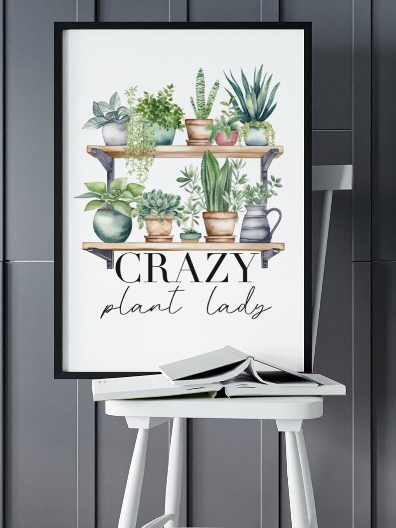 May include: A black framed print with a white background featuring a watercolor illustration of a shelf with potted plants. The text "CRAZY plant lady" is written below the shelf.