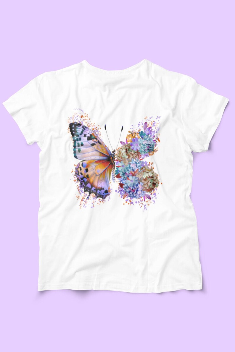 Puede incluir: Camiseta blanca con un dise&ntilde;o de mariposa colorida. La mariposa est&aacute; hecha de flores de acuarela p&uacute;rpura, azul, naranja y amarilla.