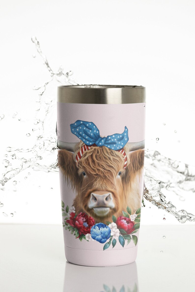 Op de afbeelding: Een lichtroze beker met een Highland-koe met een blauwe strik met sterrenpatroon en een rood-witte gestreepte hoofdband. De koe is omgeven door rode, blauwe en witte bloemaccenten. De beker heeft een zilveren rand.