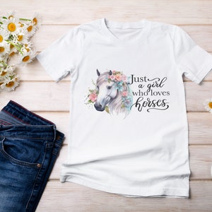 May include: White t-shirt with a watercolor illustration of a horse's head with flowers. The text "Just a girl who loves horses" is written in black cursive.