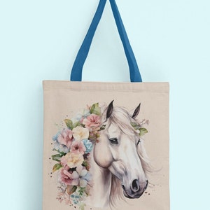 May include: A beige canvas tote bag with blue handles features a watercolor illustration of a white horse with a floral crown. The horse's head is facing the right side of the bag.