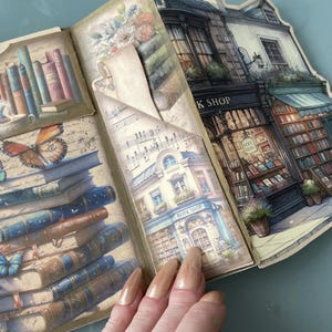 May include: A vintage-style paper craft with a book shop theme. The craft features a stack of books, a butterfly, and a paper cutout of a book shop with the text "Book Shop".