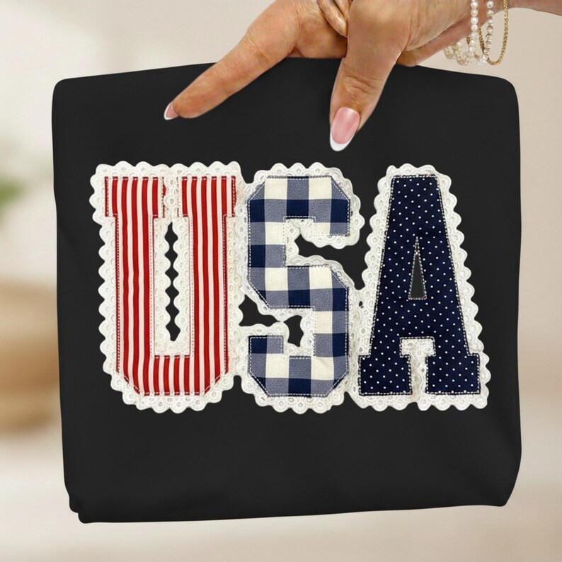 May include: Black tote bag with the word "USA" appliqued on the front. The letters are in red and white stripes, blue and white gingham, and navy blue with white polka dots, all trimmed with white lace.