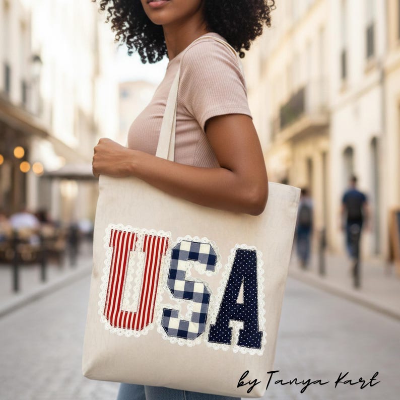 May include: A beige tote bag with the word "USA" in red and white stripes, blue and white gingham, and navy blue with white polka dots. The letters are outlined with white lace. The bag is carried by a person.