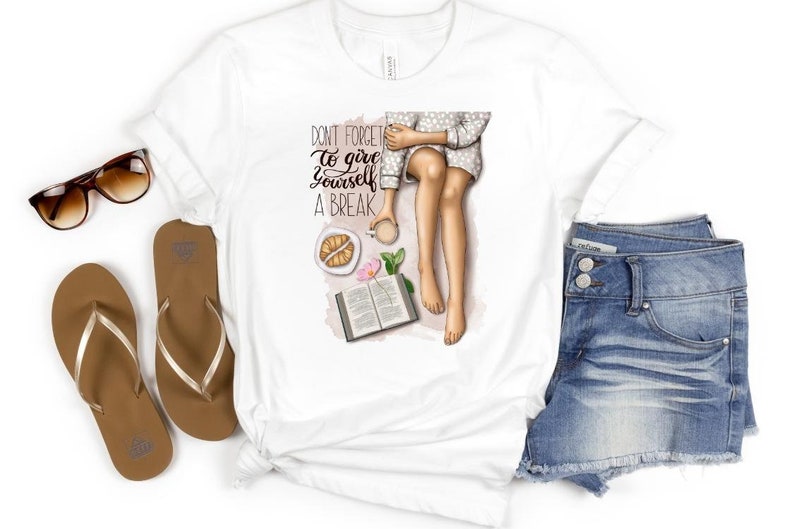 May include: White t-shirt with a graphic of a woman sitting with a book, coffee, and pastries. The text on the shirt reads "Don't forget to give yourself a break."