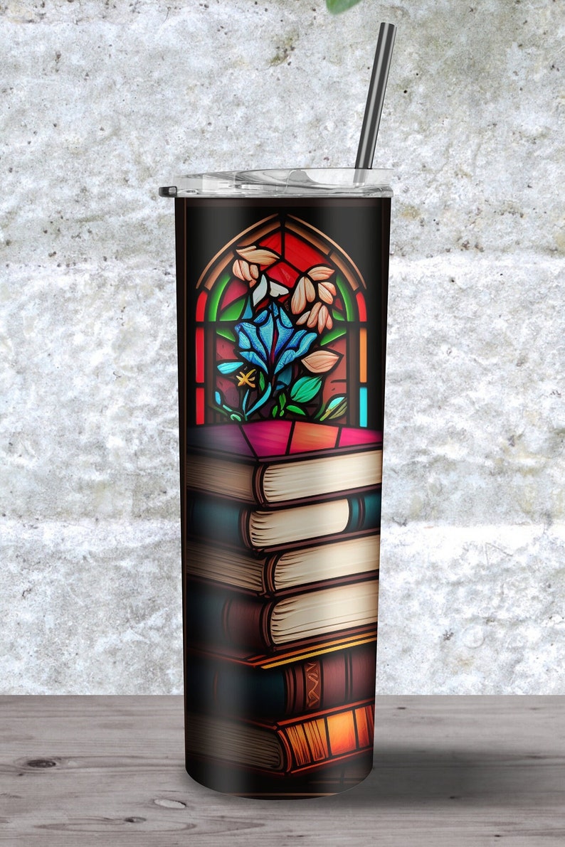 Peut inclure: Un gobelet en acier inoxydable avec un fond noir et un motif de vitrail repr&eacute;sentant une fleur bleue dans une fen&ecirc;tre. Le gobelet est surmont&eacute; d'une pile de livres.