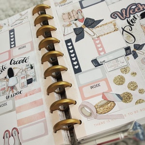 May include: A pink and white planner with gold rings. The planner has stickers with the text "Write Create Inspire" and "Plan Your Weekend with Me".