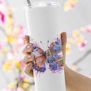 Puede incluir: Un vaso de acero inoxidable blanco con un dise&ntilde;o de mariposa y flores de colores. El vaso tiene una tapa y una pajita.
