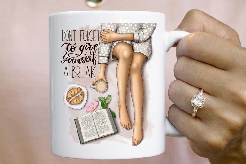 May include: White ceramic mug with a colorful illustration of a person sitting with a book, a cup of coffee, and a croissant. The text "Don't forget to give yourself a break" is printed on the mug.
