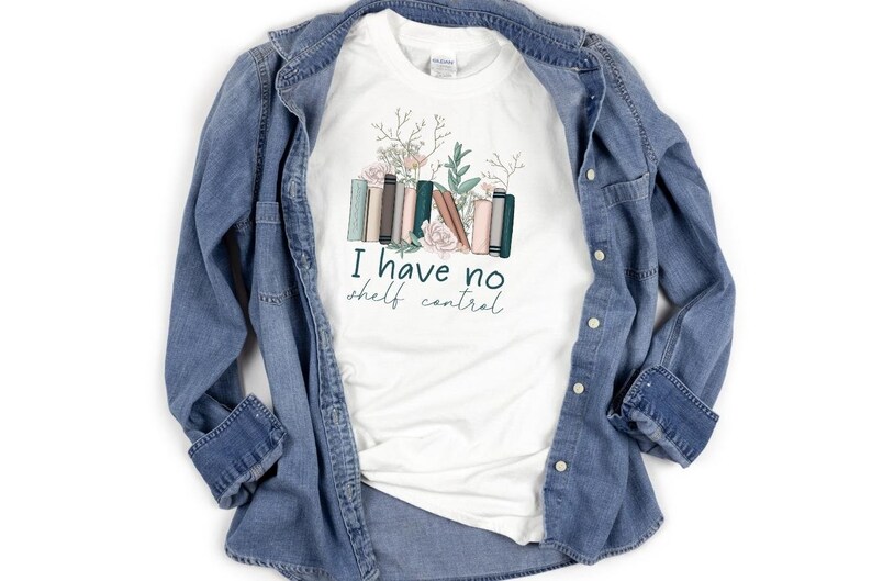 May include: White t-shirt with a graphic of a stack of books with flowers and the text "I have no shelf control".
