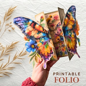 Puede incluir: Un folio imprimible con forma de mariposa colorida con alas vibrantes en tonos de azul, naranja y amarillo. El folio presenta ilustraciones florales y botánicas. El texto en la imagen dice "PRINTABLE FOLIO".