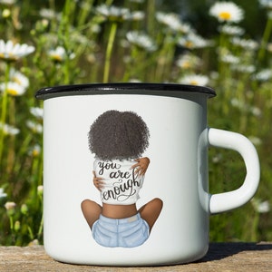 Pu&ograve; includere: Tazza smaltata bianca con bordo e manico neri. La tazza presenta un'illustrazione di una persona con capelli scuri e pantaloncini di jeans, che si abbraccia. Il testo "you are enough" &egrave; sulla maglietta.