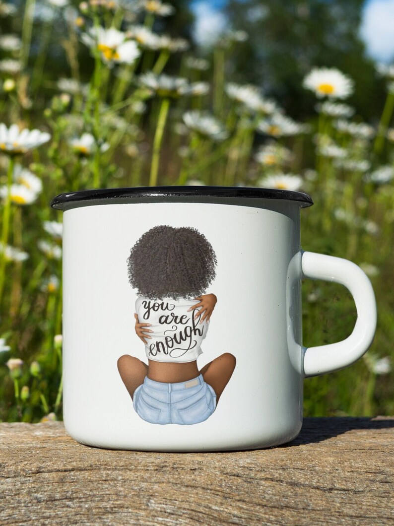 Pu&ograve; includere: Tazza smaltata bianca con bordo e manico neri. La tazza presenta un'illustrazione di una persona con capelli scuri e pantaloncini di jeans, che si abbraccia. Il testo "you are enough" &egrave; sulla maglietta.