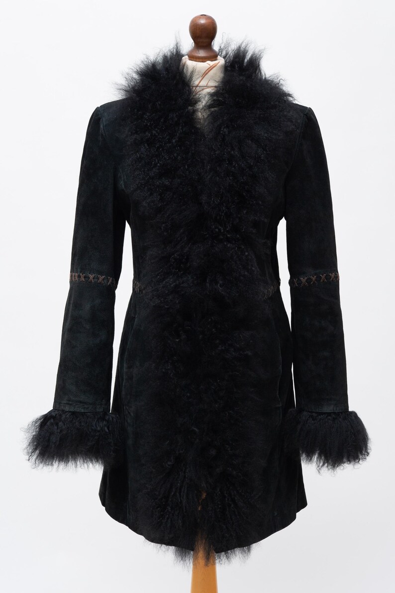 May include: A black suede coat with a faux fur collar and cuffs. The coat features a tailored silhouette with decorative stitching on the sleeves and a flared hem. The fur trim adds a touch of luxury to this outerwear piece.
