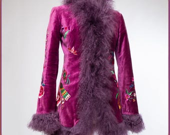 May include: A magenta velvet coat with floral embroidery and a fluffy, lavender-colored trim. The coat features long sleeves and a high collar, with the fluffy trim extending down the front and around the cuffs. The embroidery includes colorful flowers and leaves.