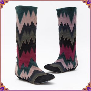 May include: A pair of knee-high boots with a colorful chevron pattern in shades of green, black, pink, and red. The boots have a pointed toe and a low heel.