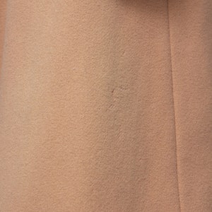 May include: Close-up of a light brown fabric with a subtle texture. The fabric has a slight seam running vertically down the right side.