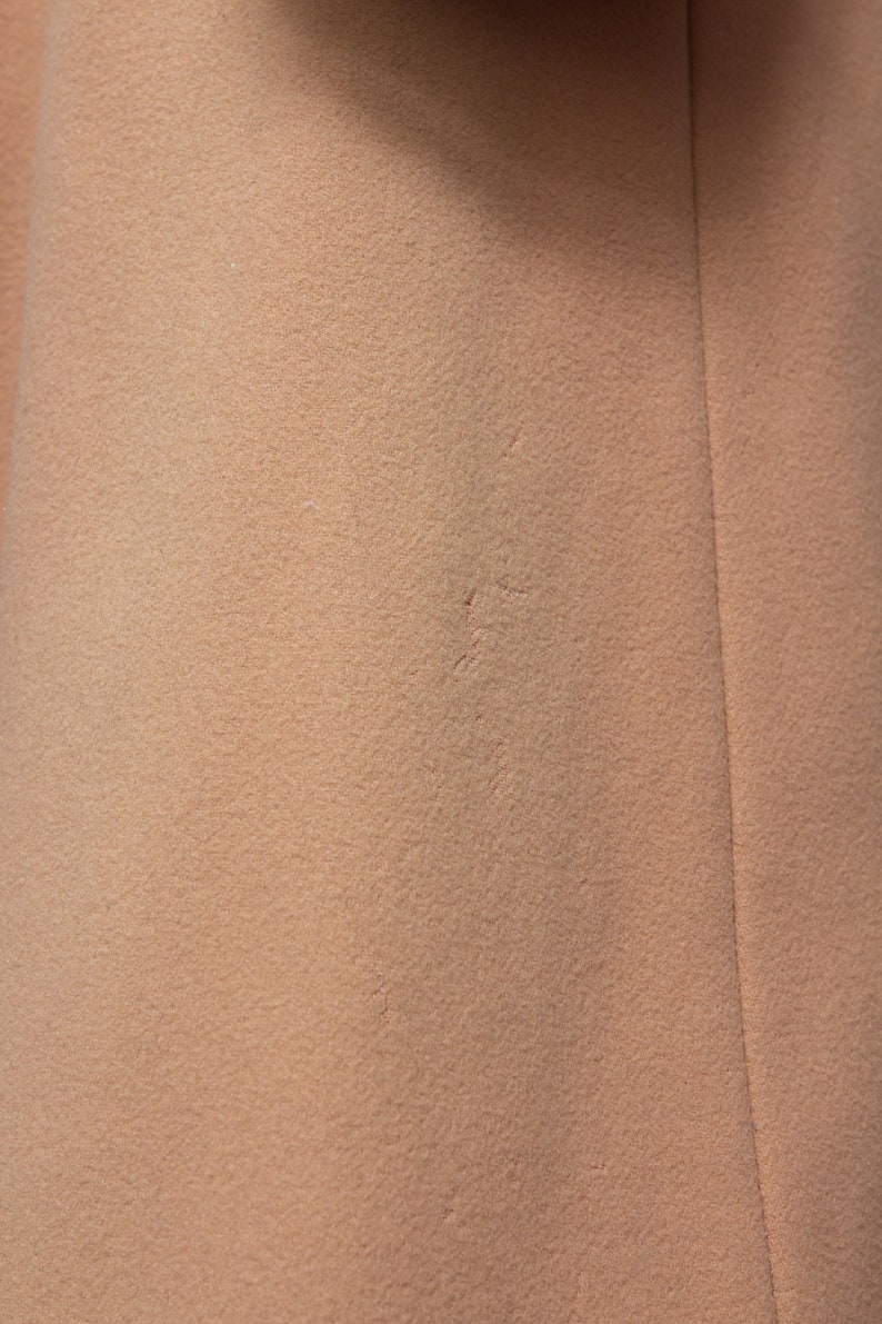 May include: Close-up of a light brown fabric with a subtle texture. The fabric has a slight seam running vertically down the right side.