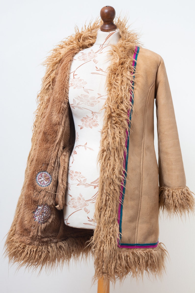 May include: A brown faux fur lined suede coat with a pink and teal trim. The coat has decorative embroidery on the front.