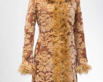 May include: A brown and gold patterned coat with a faux fur collar and trim. The coat has a long, fitted silhouette and a button closure.