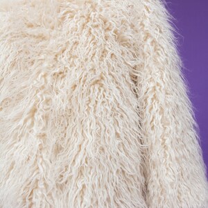 May include: A white fluffy faux fur jacket with long sleeves.