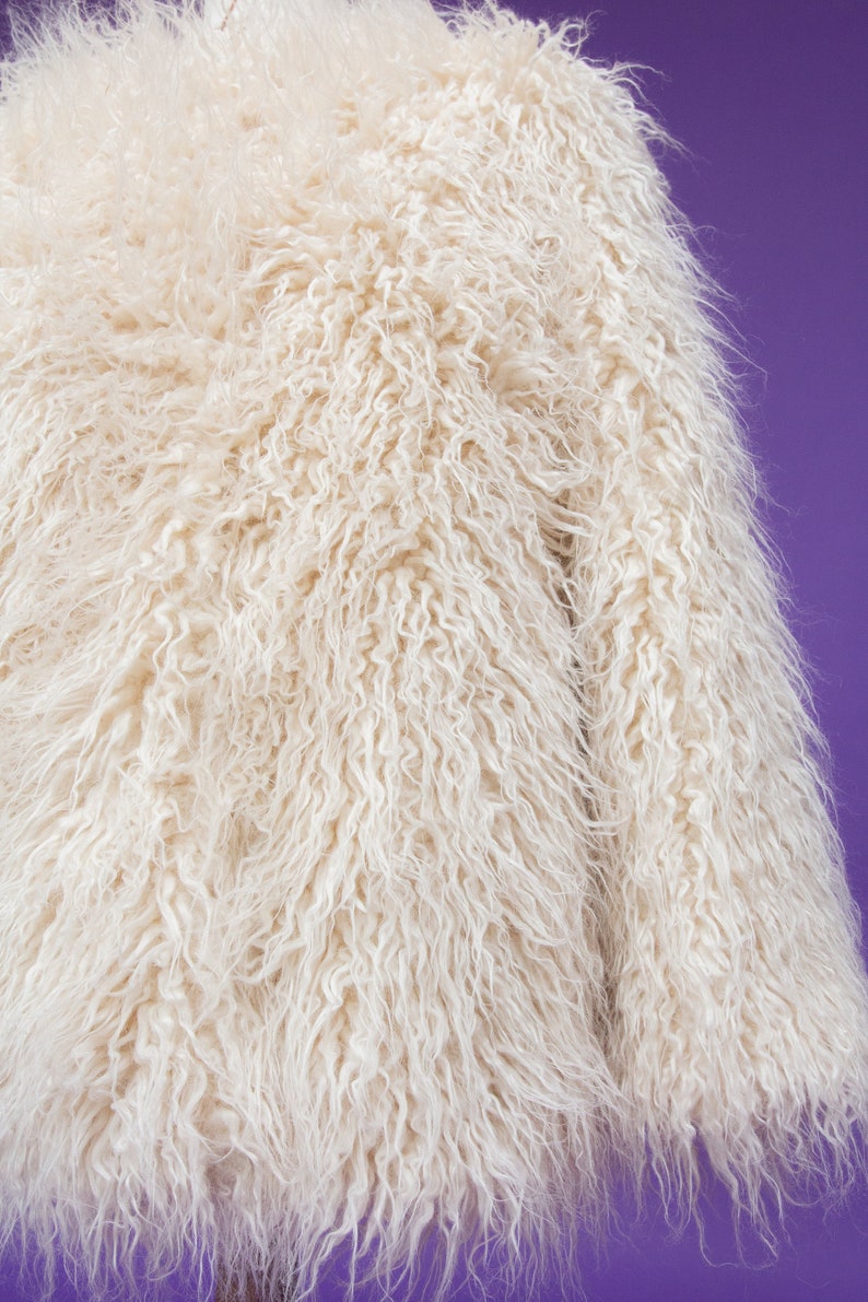 May include: A white fluffy faux fur jacket with long sleeves.