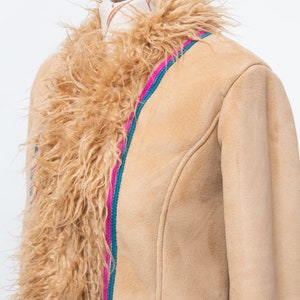 May include: A tan suede jacket with a faux fur collar. The jacket has a pink and teal trim along the front zipper.