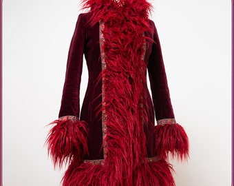 May include: A burgundy velvet coat with vibrant red faux fur trim. The coat features a high collar, cuffs, and a central panel of plush fur. Intricate embroidered detailing accents the edges, creating a striking, bohemian-inspired garment.