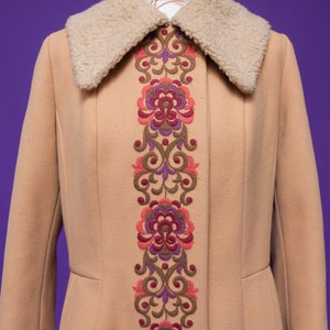 May include: A tan long coat with a faux fur collar and a floral embroidered design down the front.