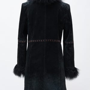 May include: A black coat with a faux fur collar and cuffs. The coat features decorative stitching across the waist and on the sleeves. The coat is displayed on a wooden hanger against a white background. The coat is a knee-length style.