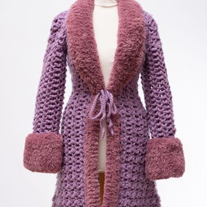 May include: A long, purple crocheted cardigan with a faux fur collar and cuffs. The cardigan has a tie at the waist and a loose fit.