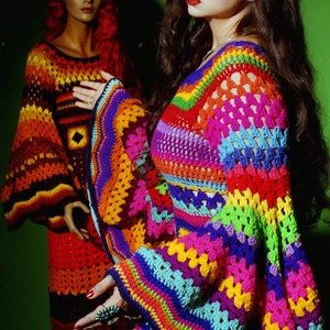 May include: A vibrant, rainbow-colored crochet top with flared sleeves. The top features a mix of bright colors including pink, blue, yellow, and green. A mannequin in the background wears a similar crochet dress in shades of orange and red.