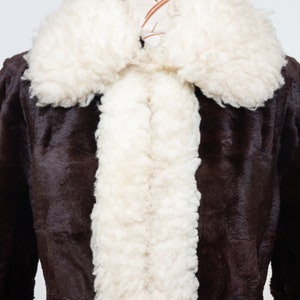 May include: A brown faux fur coat with a white faux fur collar and lining. The coat is on a mannequin.