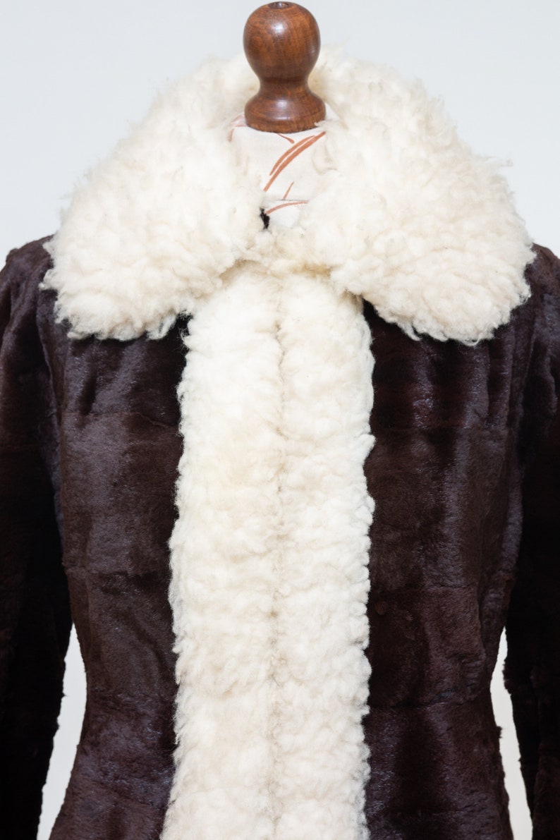 May include: A brown faux fur coat with a white faux fur collar and lining. The coat is on a mannequin.