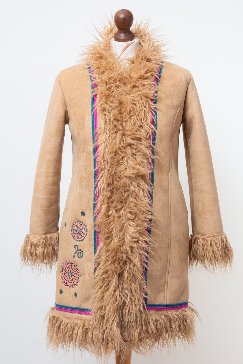 May include: A long, brown suede coat with a faux fur collar and trim. The coat has a colorful embroidered design on the front and a pink and blue stripe down the front.