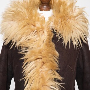 May include: A dark brown coat with a tan fur collar. The coat has a classic design with a plush, textured fur collar that frames the neckline. The fur is a light tan color, contrasting with the dark brown of the coat.