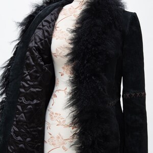 May include: Black suede coat with a faux fur trim and lining. The coat features a quilted interior and decorative stitching on the sleeves. The coat is displayed on a mannequin.
