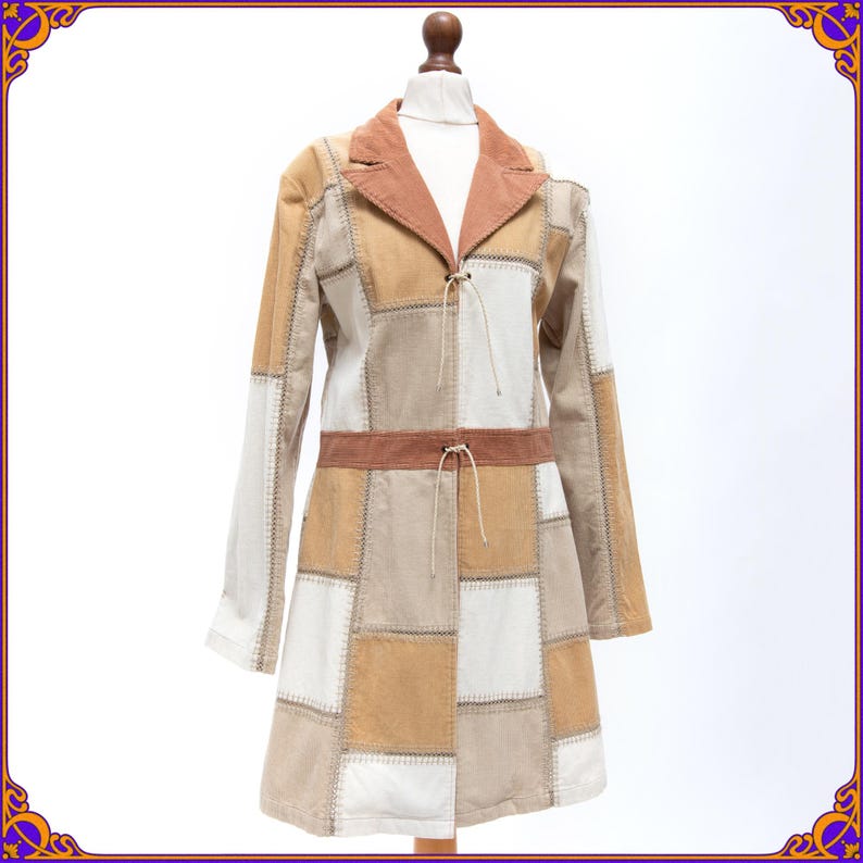 May include: A brown and beige patchwork coat with a brown collar and a drawstring closure. The coat has a long, fitted silhouette and is made of a soft, textured fabric.