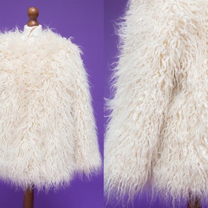 May include: A white faux fur jacket with long sleeves. The jacket is soft and fluffy.