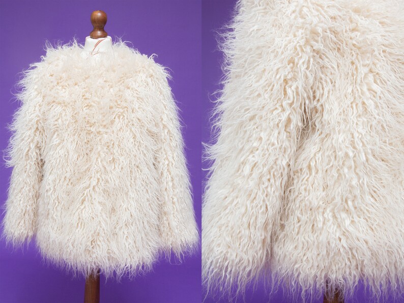 May include: A white faux fur jacket with long sleeves. The jacket is soft and fluffy.