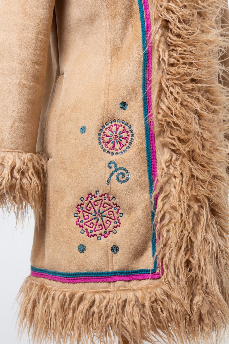 May include: A brown suede jacket with a long, shaggy fur collar and trim. The jacket features colorful embroidered designs with geometric patterns and sequins.