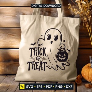 May include: Beige tote bag with a black Halloween-themed design. The design features a cartoon ghost holding a jack-o'-lantern and the words "Trick or Treat". The bag is made of a light-colored fabric and is suitable for carrying items.