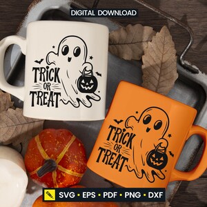 May include: Two ceramic mugs with Halloween-themed designs. One is cream-colored, the other is orange. Both feature a ghost holding a jack-o'-lantern and the words "Trick or Treat". The mugs are on a rustic tray with fall decorations.