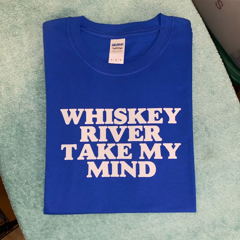 Peut inclure: Un t-shirt bleu royal avec du texte blanc qui dit "Whiskey River Take My Mind".