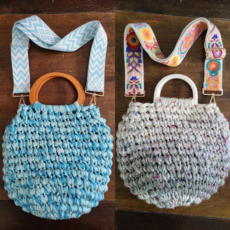 May include: Two round woven handbags with decorative straps. One is light blue with a wooden handle and a light blue and white patterned strap. The other is gray with a white handle and a floral strap.