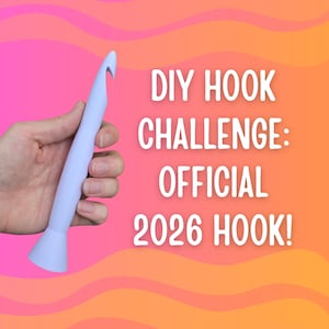 May include: A light blue crochet hook held against a gradient pink and orange background. The text reads "DIY HOOK CHALLENGE: OFFICIAL 2026 HOOK!" in white. The hook has a flared base and a curved hook end.