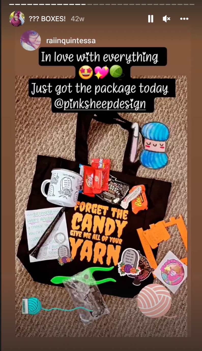Puede incluir: Una bolsa de tela negra con el texto "Forget the Candy Give me all of your Yarn" en naranja y negro. La bolsa est&aacute; llena de hilo, una taza, dulces y otros materiales de artesan&iacute;a.
