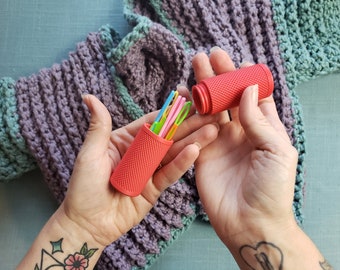 May include: A red plastic case with a textured surface holds a set of colourful crochet hooks. The case is open and the hooks are visible.