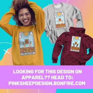 May include: Mustard yellow sweatshirt, gray long-sleeve shirt, and maroon hoodie. Each garment features a tarot card design with the text "THE KNITTER." The design includes hands knitting under a sun. The bottom of the image has the text "LOOKING FOR THIS DESIGN ON APPAREL?? HEAD TO: PINKSHEEPDESIGN.BONFIRE.COM."